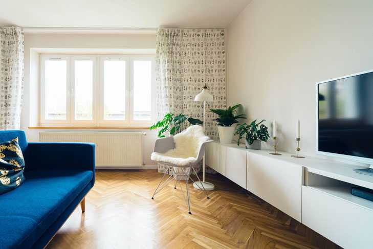 Ein minimalistisch eingerichtetes Wohnzimmer mit Couch und Fernseher – der eigentliche Wohnraum wird im WEG als Sondereigentum bezeichnet.