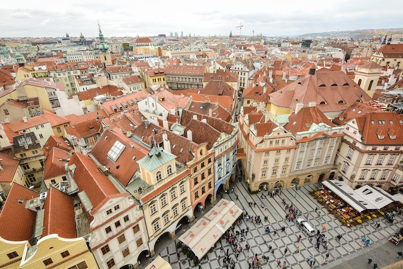 Man sieht Dächer in einer Stadt und einen Marktplatz mit vielen Menschen. Im folgenden Kapitel erfahren Sie, was zu den Aufgaben einer WEG-Verwaltung gehört, unter anderem auch die Instandhaltung des Gemeinschaftseigentums wie etwa der Dächer.