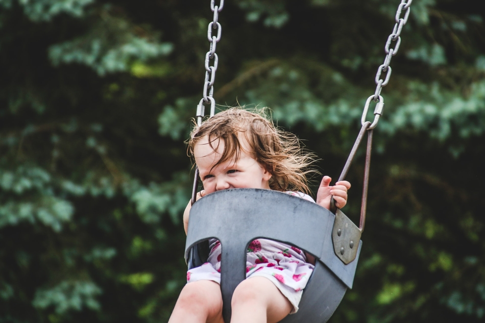 Ein Kleinkind sitzt in einer Schaukel. Welche Geräte auf dem Grundstück eines Mehrfamilienhauses aufgestellt werden dürfen, sorgt in WEGs häufig für Streit.