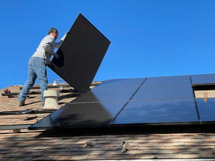 Ein Mann installiert eine Solaranlage auf einem Dach.
