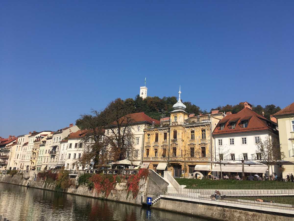 Wir sehen Reihenhäuser in der slowenischen Hauptstadt Ljubljana, im Hintergrund ist ein Schloss zu sehen. In diesem Beitrag erfahren Sie interessante Informationen zum Thema Verwaltervollmacht für WEG-Verwalter