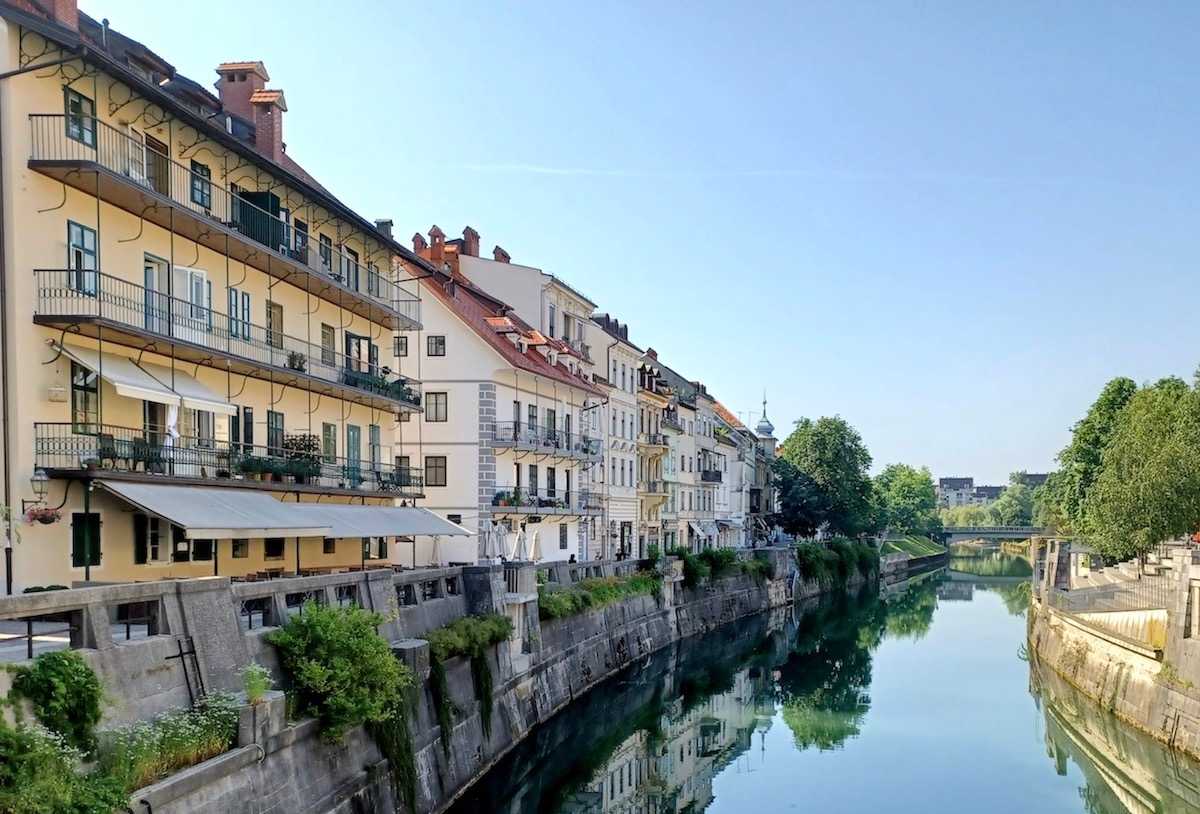 Links sind Gebäude in der Altstadt von Ljubljana zu sehen, in der Mitte ist der Fluss Ljubljanica.