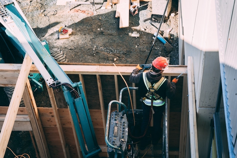 Ein Bauarbeiter repariert eine Hauswand. Jetzt erfahren Sie, auf welche Tätigkeiten sich die Vollmachtsurkunde für WEG-Verwalter erstreckt. Unter anderem gehört zu dessen Befugnissen auch der Abschluss von Werkverträgen.
